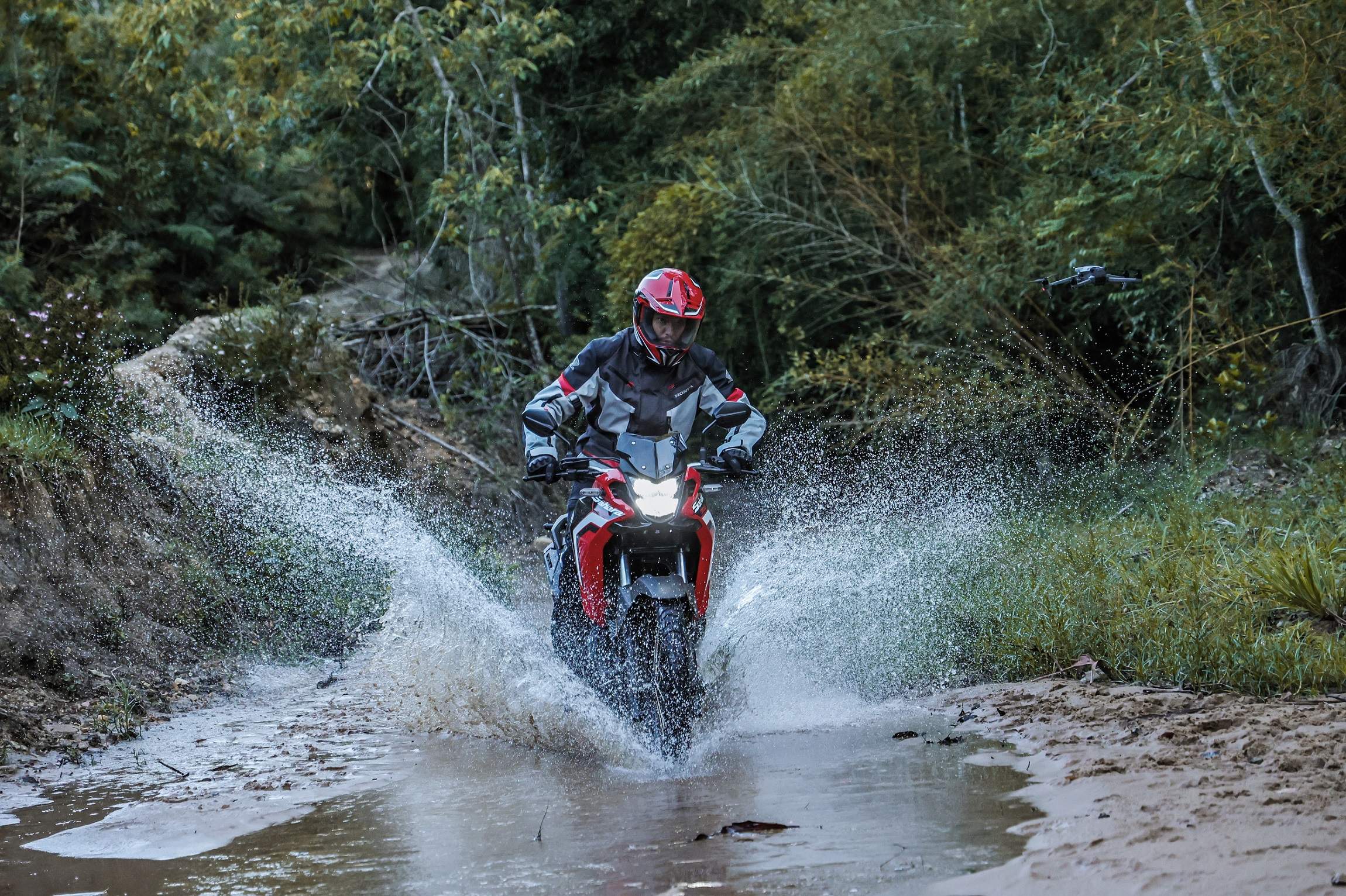 Piloto da Honda em estrada de chão passando em poça de água