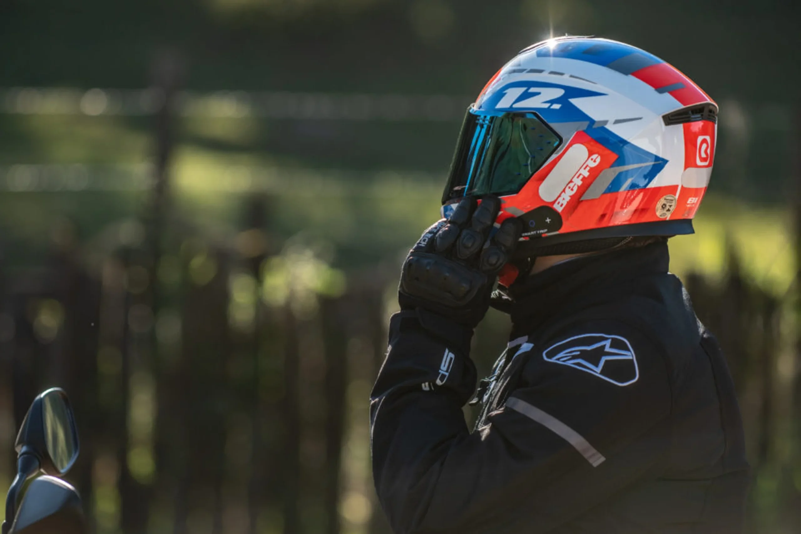 Homem colocando um capacete de motociclismo na cabeça